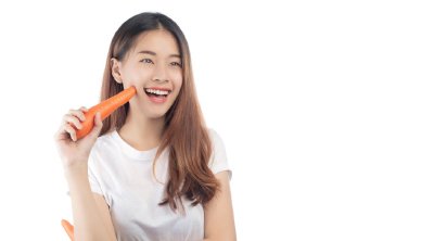 ผู้หญิงผมยาว ยืนถิอแครอท ยิ้มกว้าง พื้นหลังขาว ครอปมุมใกล้